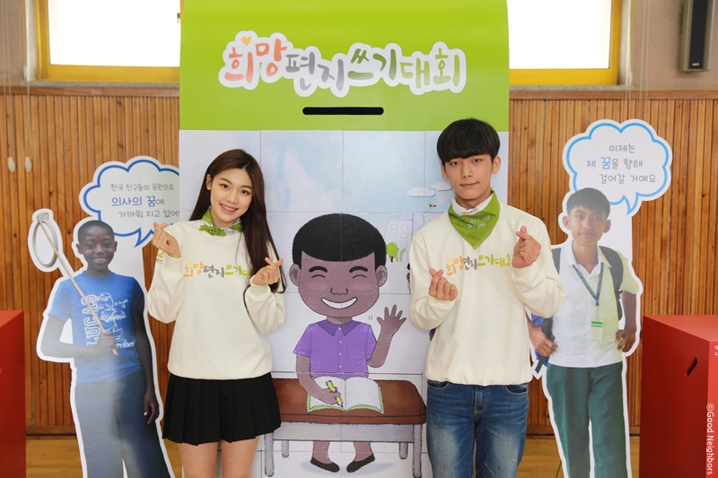 EBS 생방속 톡톡 보니하니의 MC 보니와 하니가 사이먼 판넬 앞에서 손하트하며 사진찍는 모습