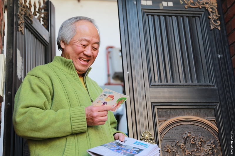 남자 어르신이 그림엽서를 보며 미소짓는 모습