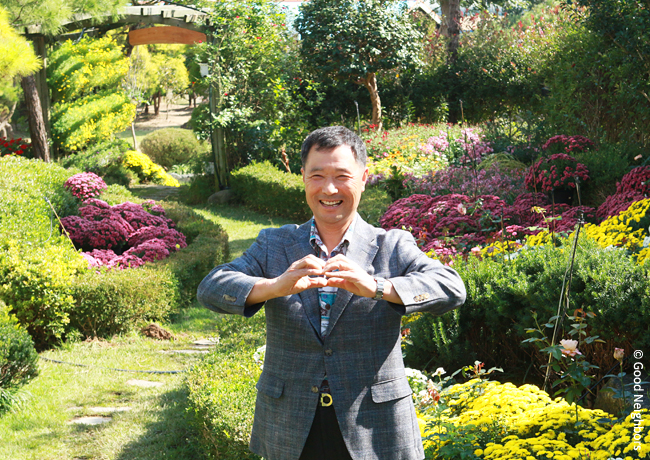 정원에서 손으로 하트를 그리며 환하게 웃고 있는 이선행 회원 이미지