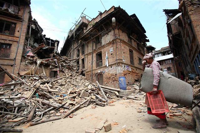26일 네팔 수도 카트만두에서 북동쪽에 있는 박타푸르의 한 여성이 지진으로 무너진 집 앞에서 망연자실한 모습으로 서 있다.  박타푸르/UPI 연합뉴스